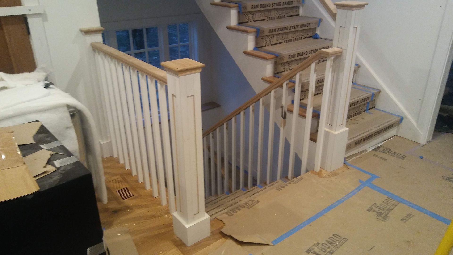 A staircase with a white railing and wooden steps is being built in a house.