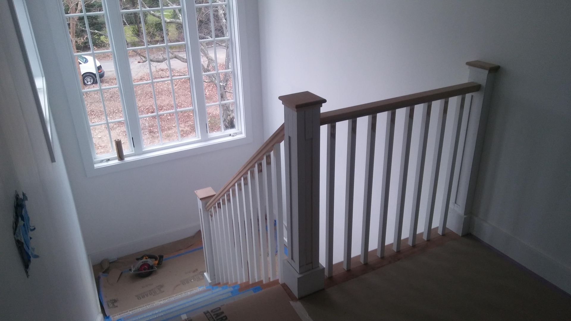 A staircase with a wooden railing and a window.