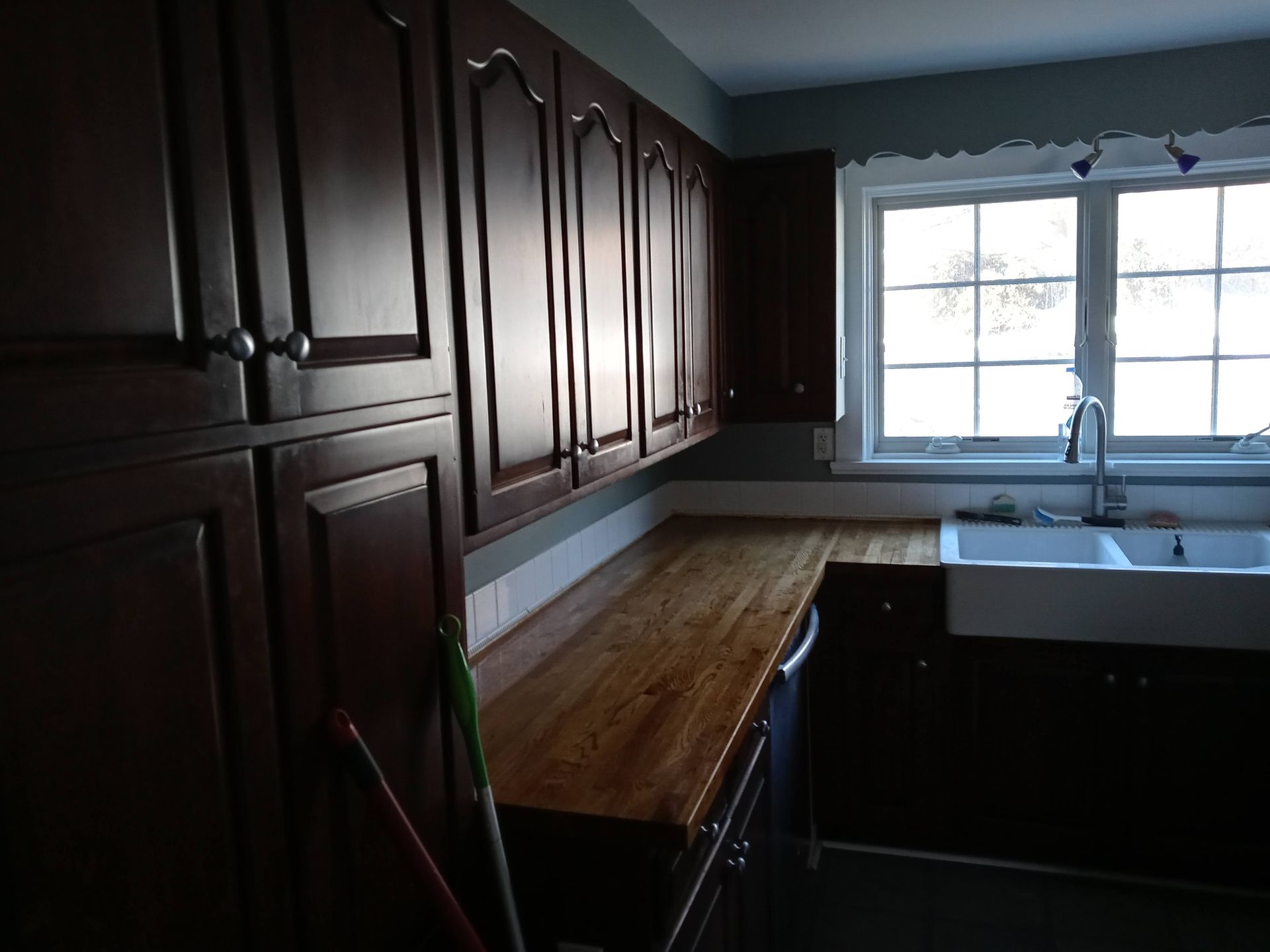 A kitchen with dark cabinets and a white sink