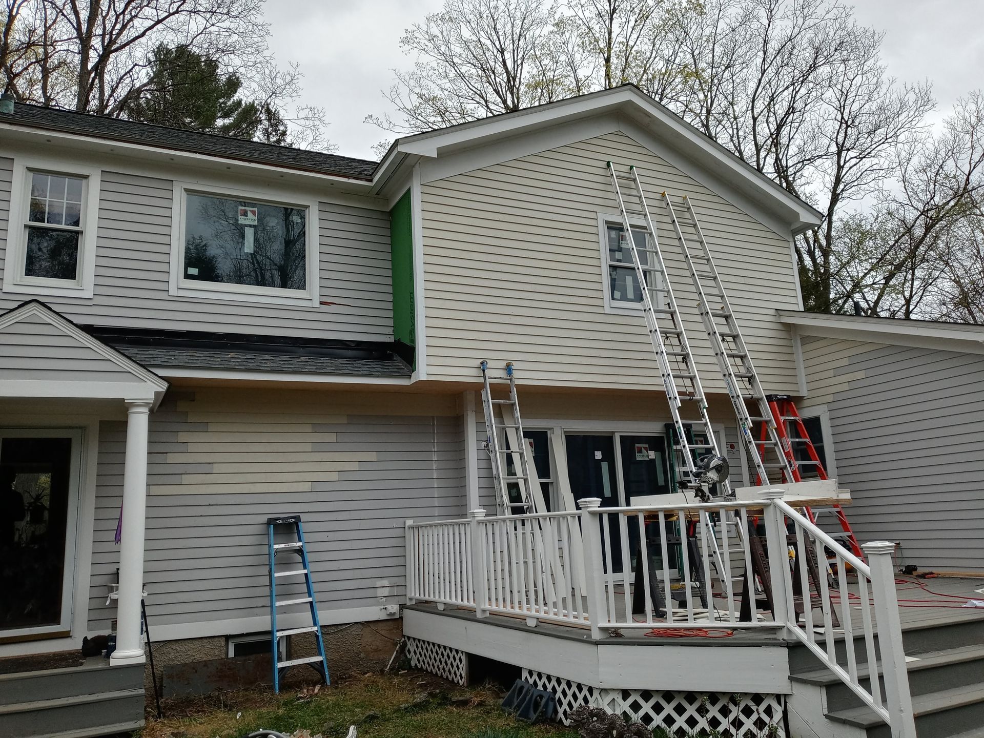 A house with a ladder on the side of it is being painted.