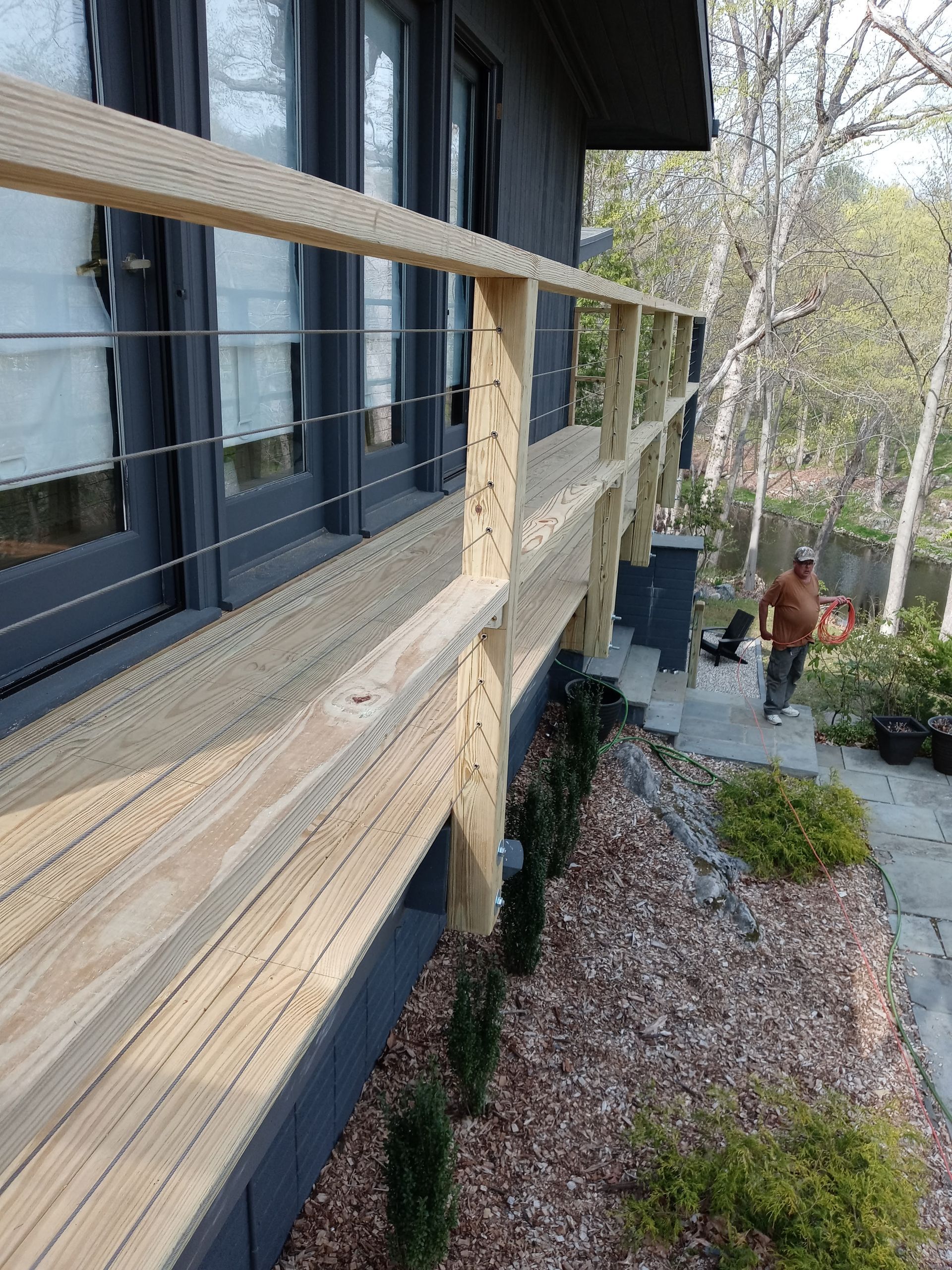 A man is standing on a wooden deck next to a house.