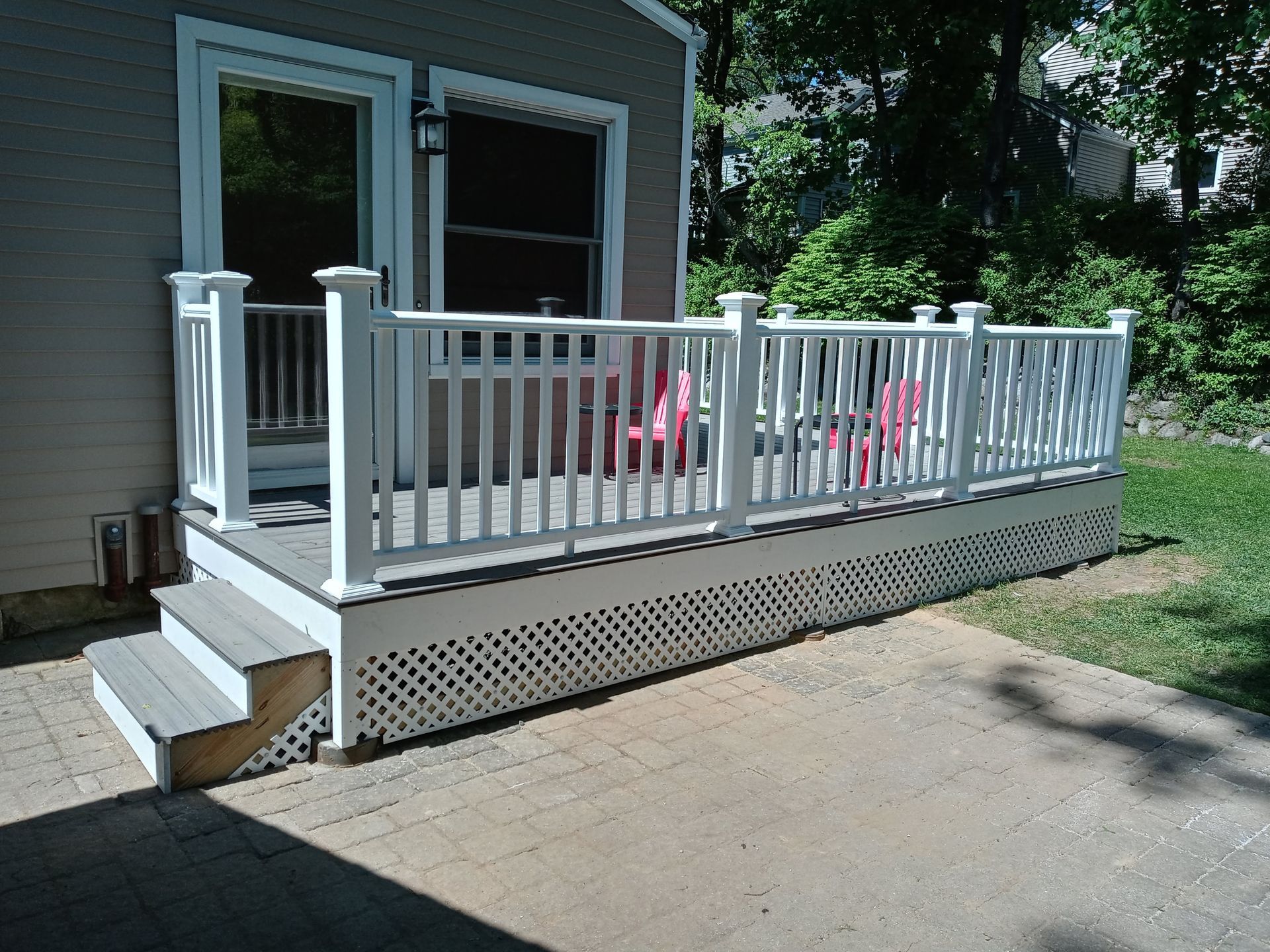 A deck with a white railing and chairs on it