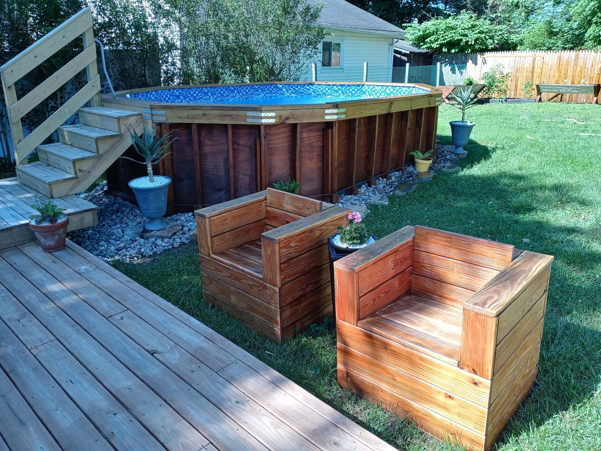 A wooden deck with chairs and a pool in the background