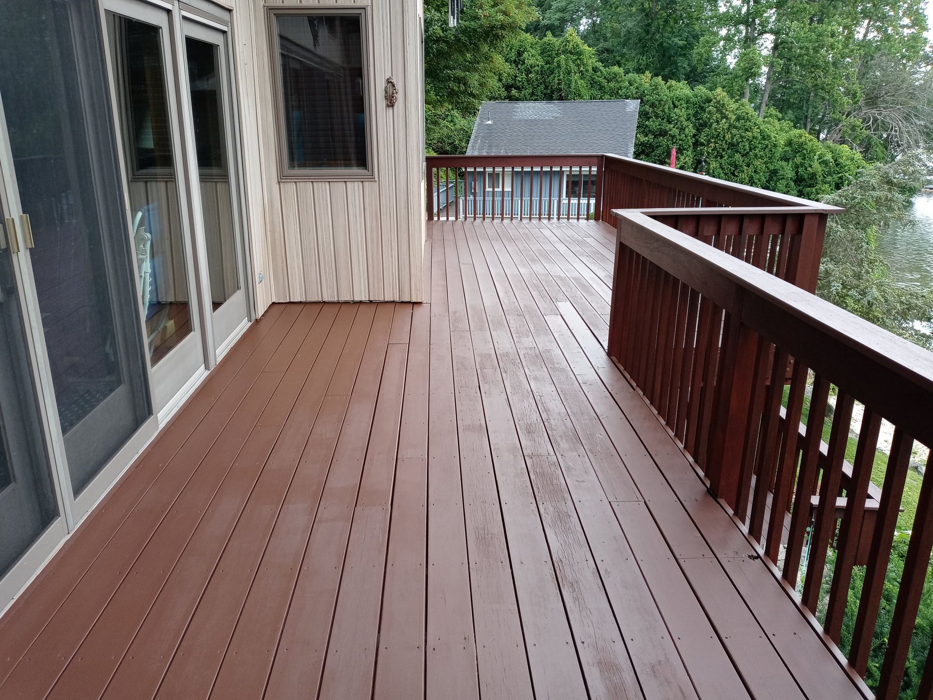 A large wooden deck with a railing and sliding glass doors