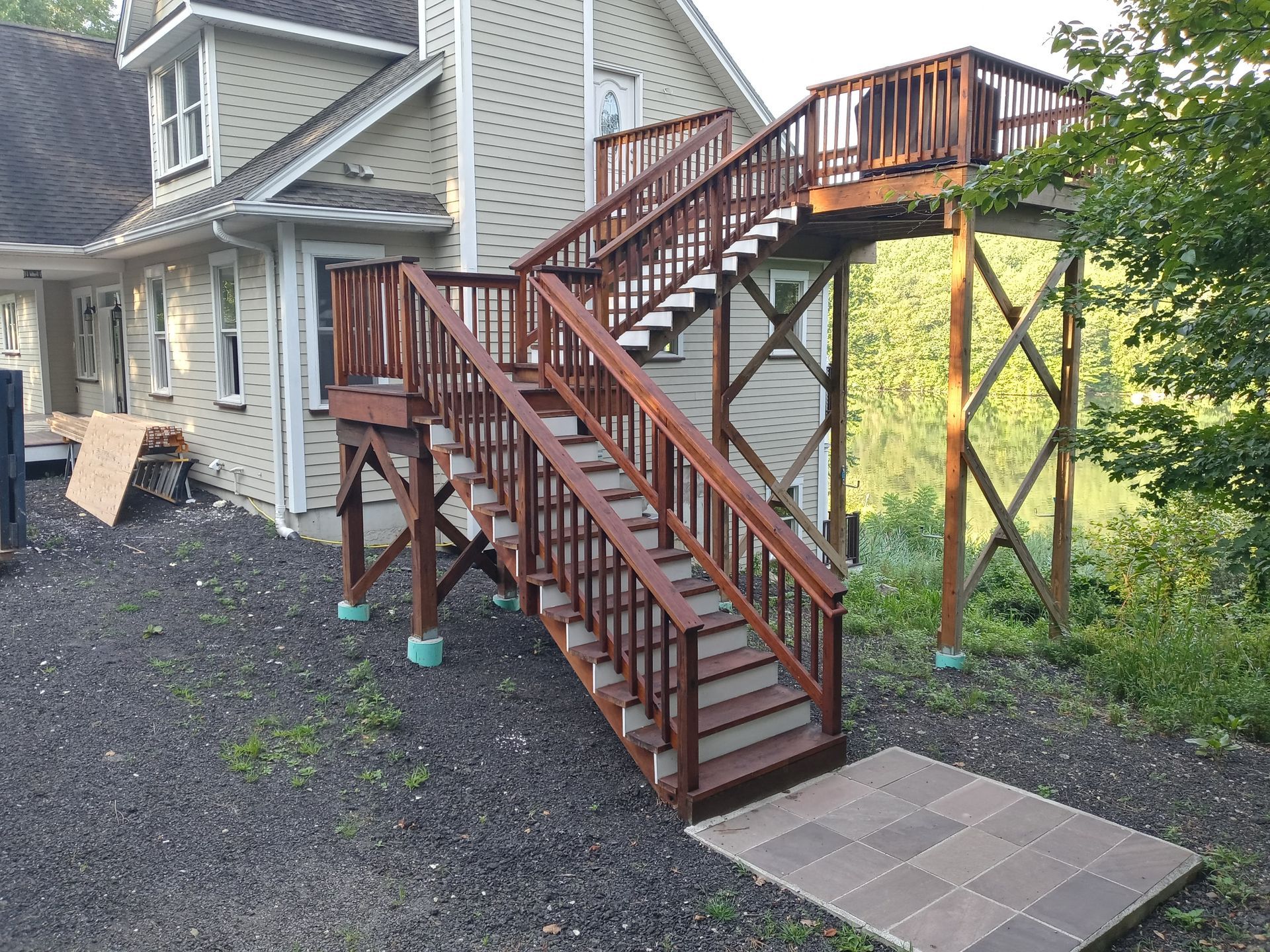 A wooden deck with stairs leading up to it is in front of a house.