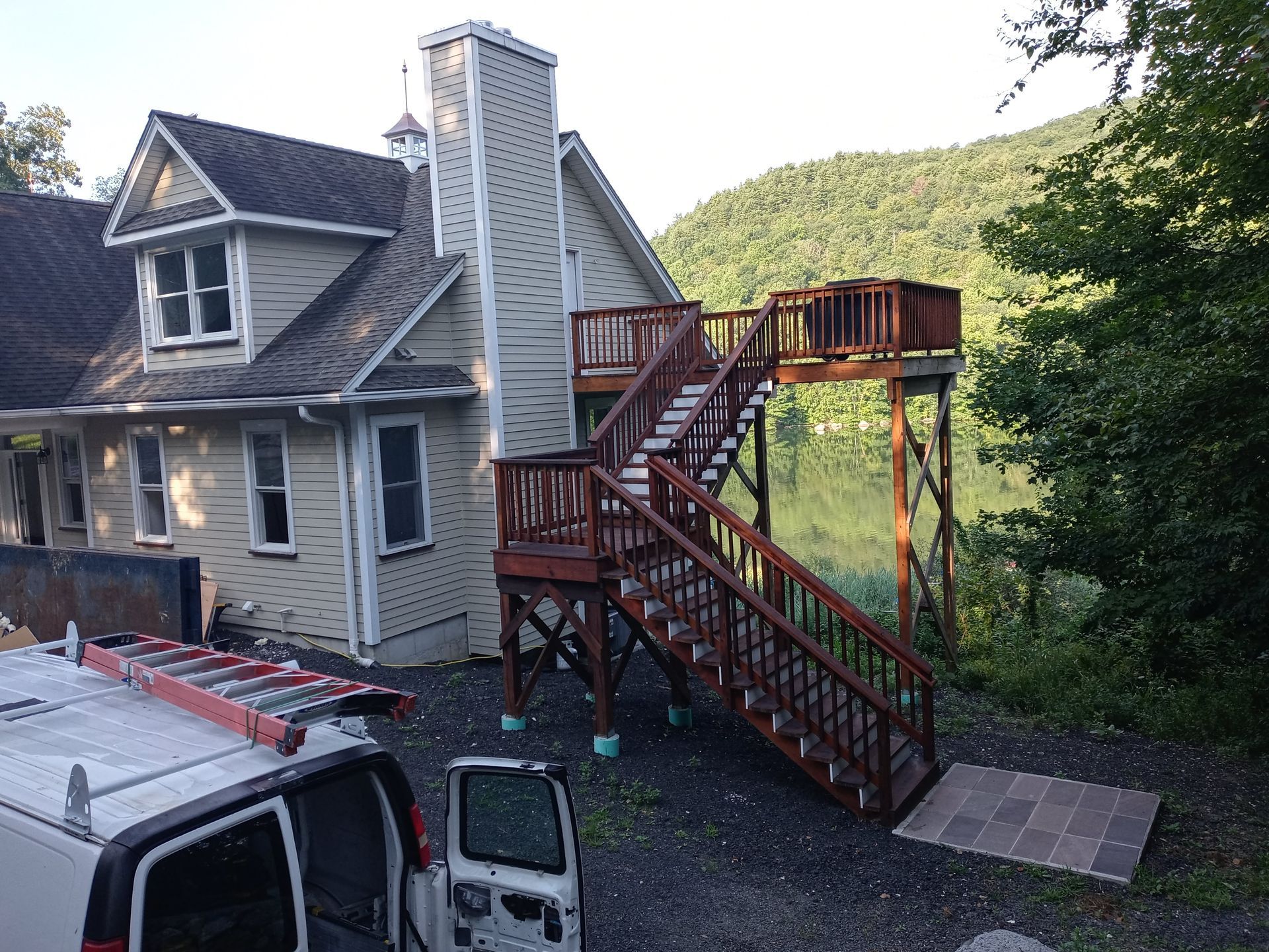 A white van is parked in front of a house with stairs