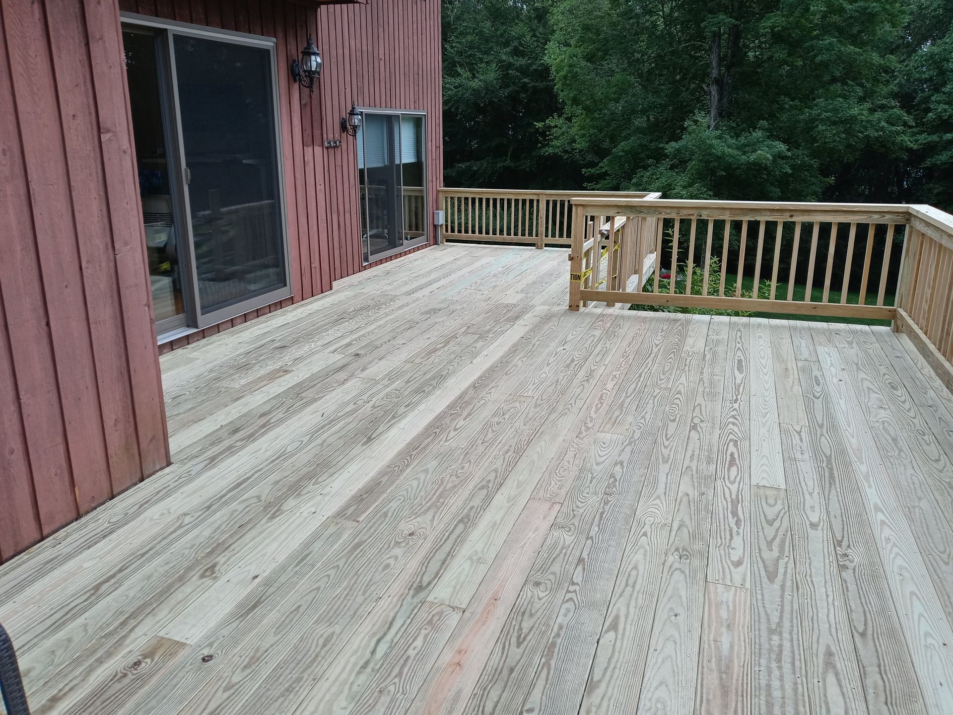 A large wooden deck with a railing in front of a house.