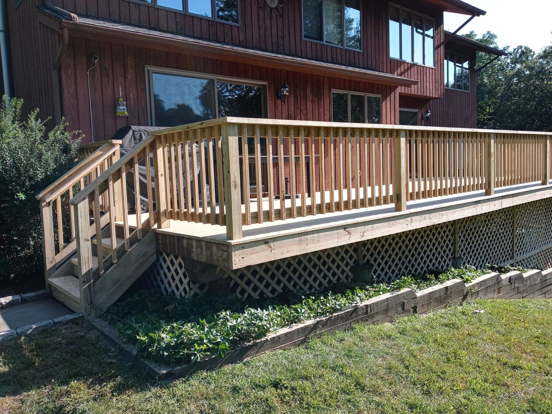 A wooden deck with stairs is in front of a house.