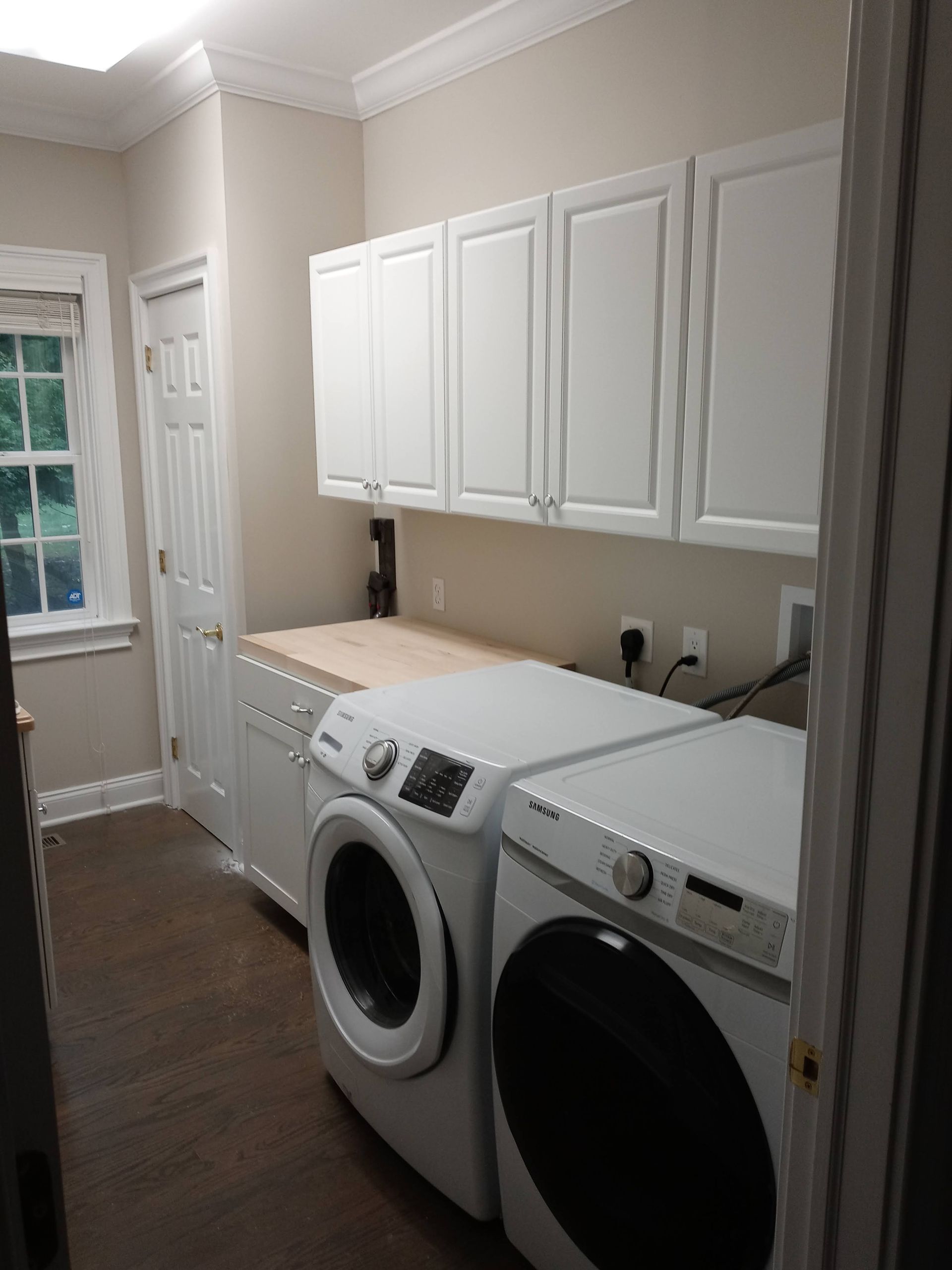 A laundry room with a washer and dryer and white cabinets.