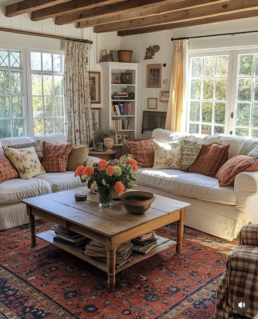A living room filled with furniture and a coffee table with a vase of flowers on it.