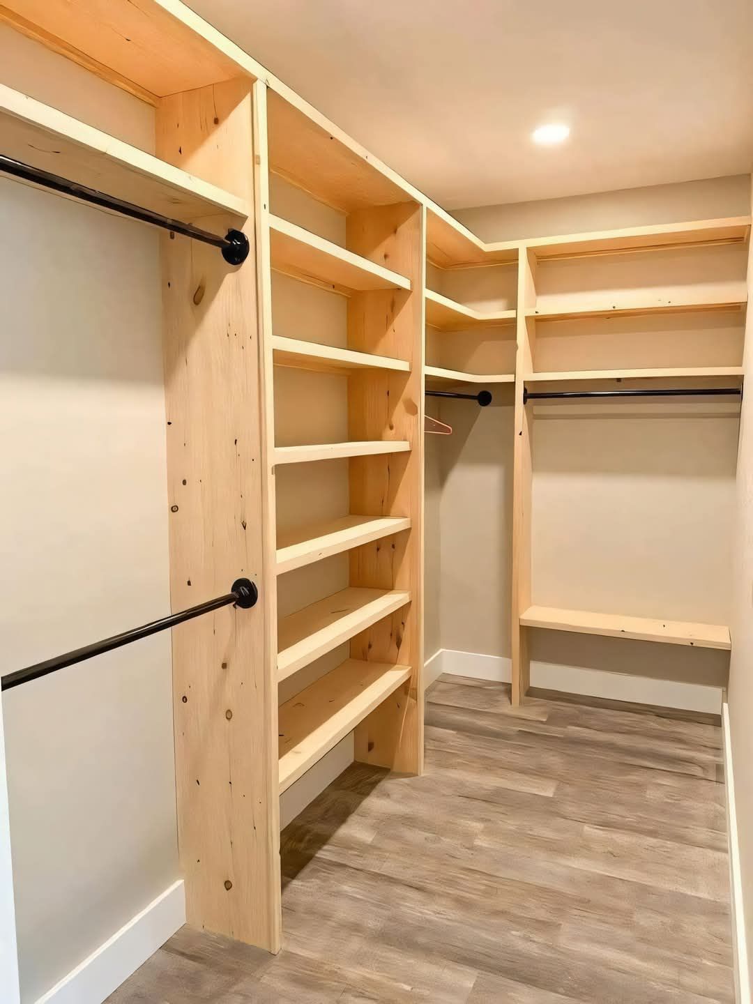 A walk in closet with wooden shelves and hanging racks.