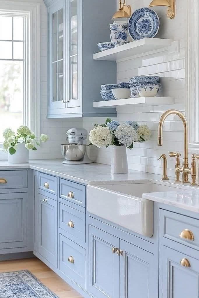 A kitchen with blue cabinets , white counter tops , a sink and a window.