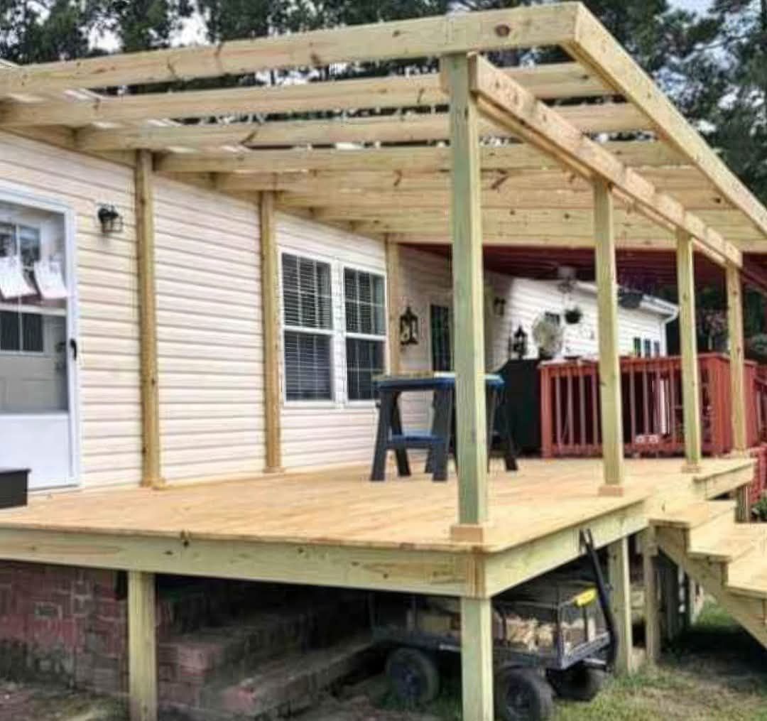 A wooden deck is sitting in front of a house.