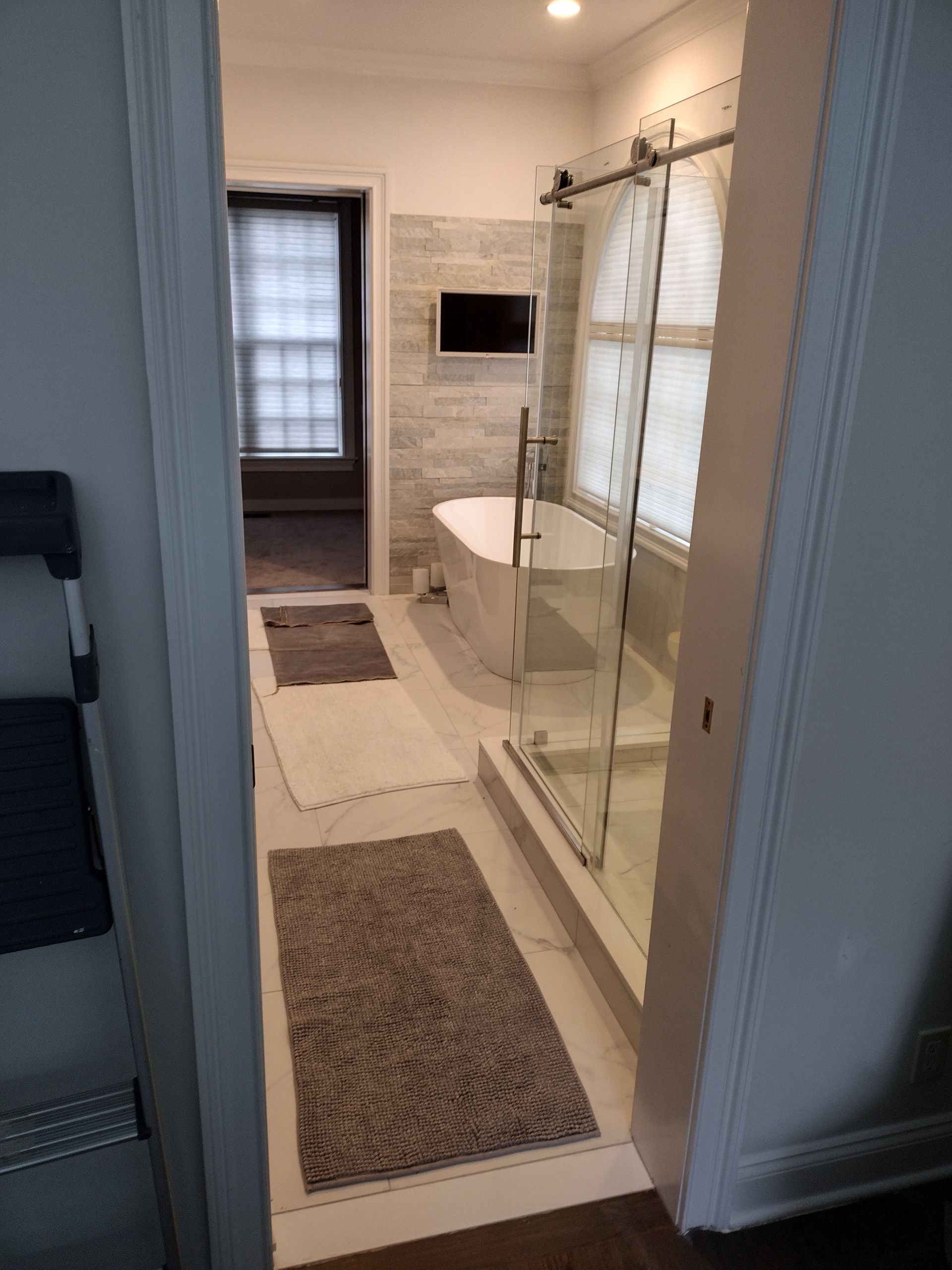 A bathroom with a tub , shower , and television.