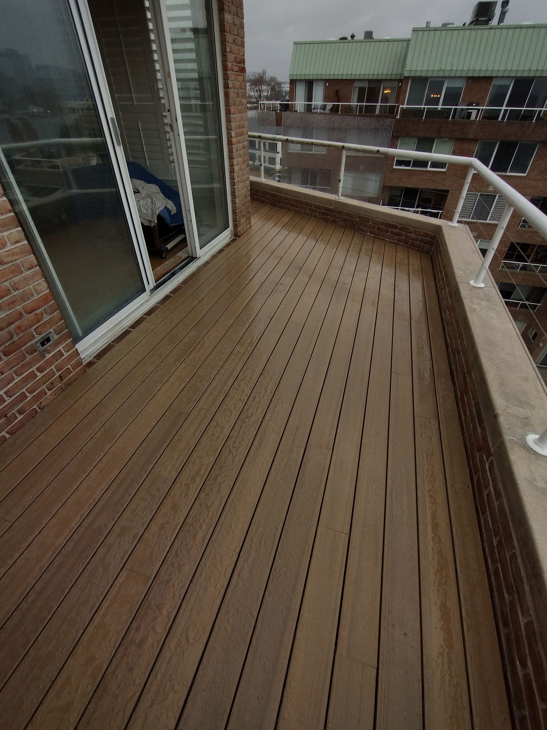 A balcony with a wooden deck and sliding glass doors