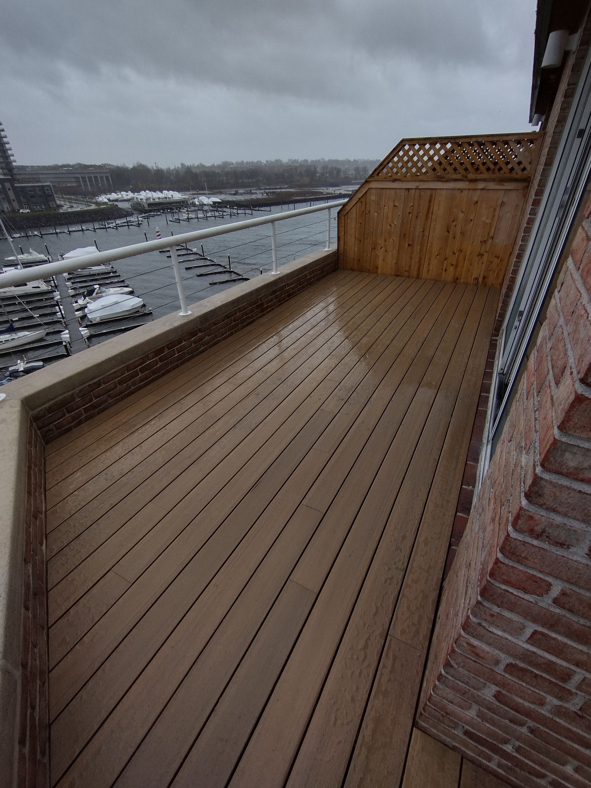 A balcony with a wooden deck and a view of the water.