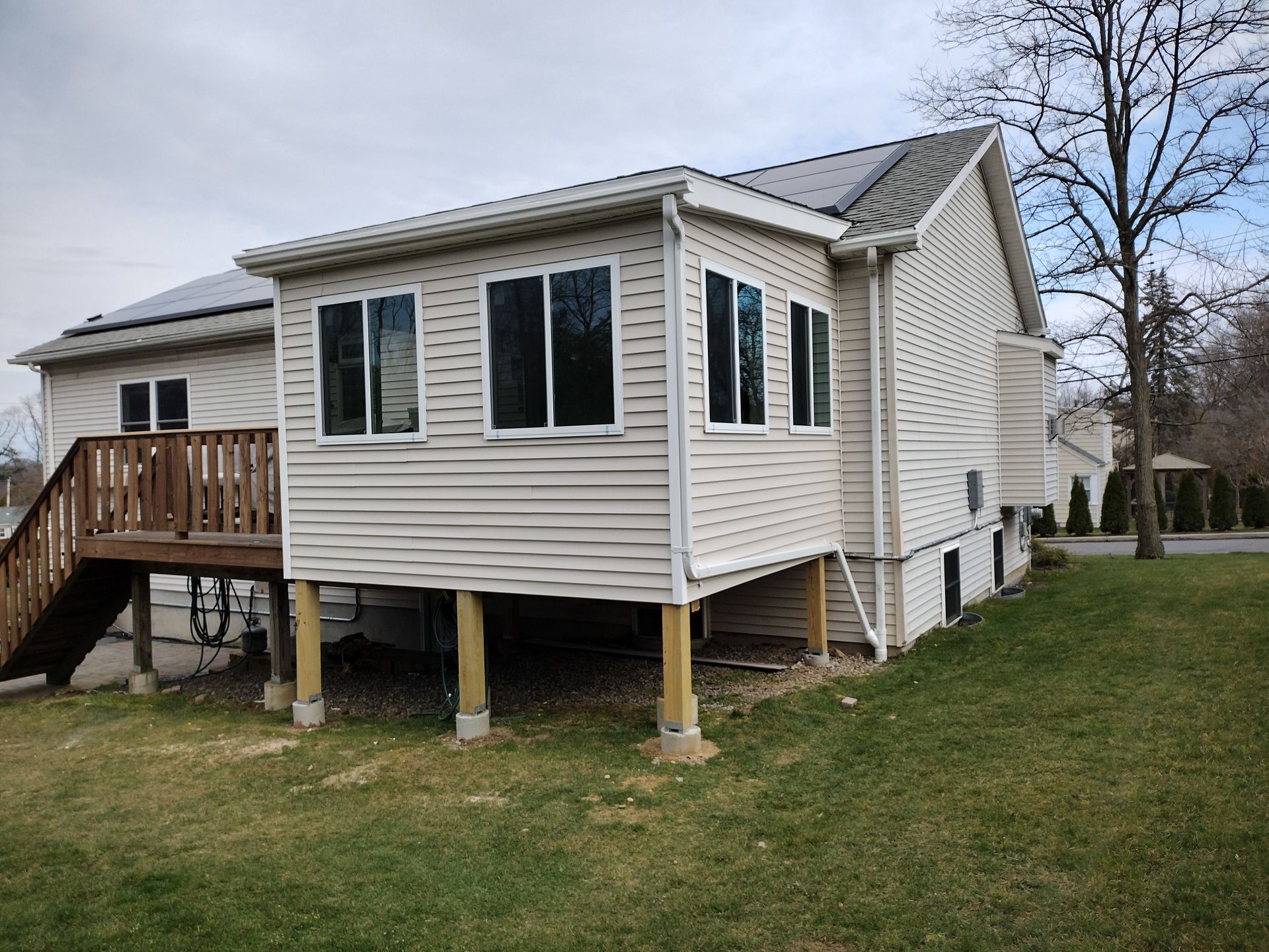 A house with a sunroom and a deck in the backyard.