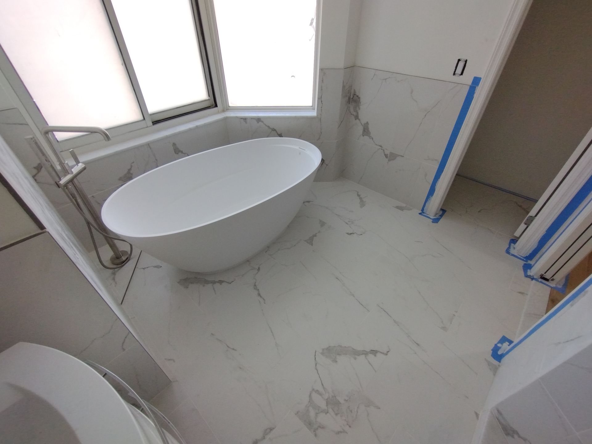 A bathroom with a bathtub , toilet , and window.