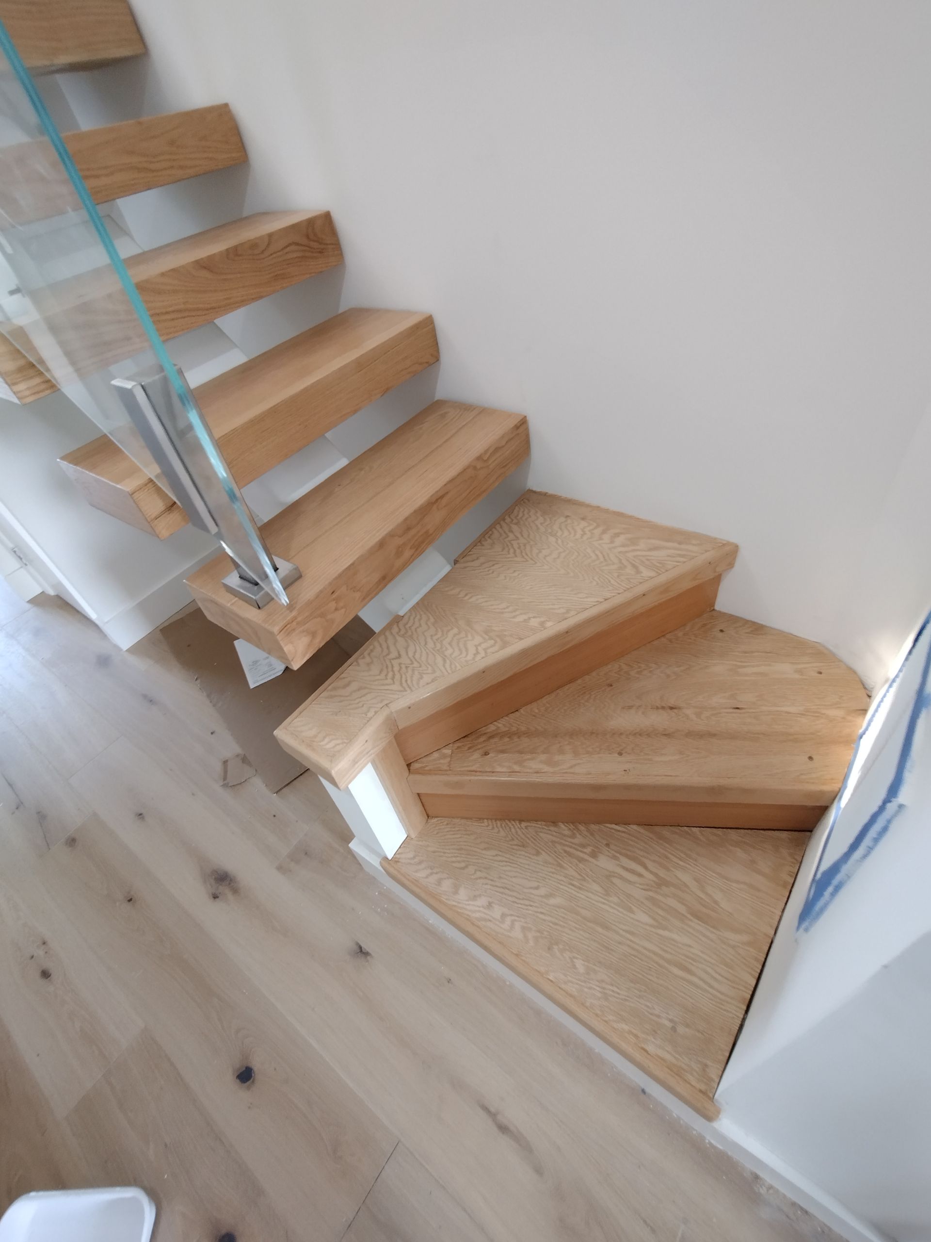 A wooden staircase with a glass railing in a room.