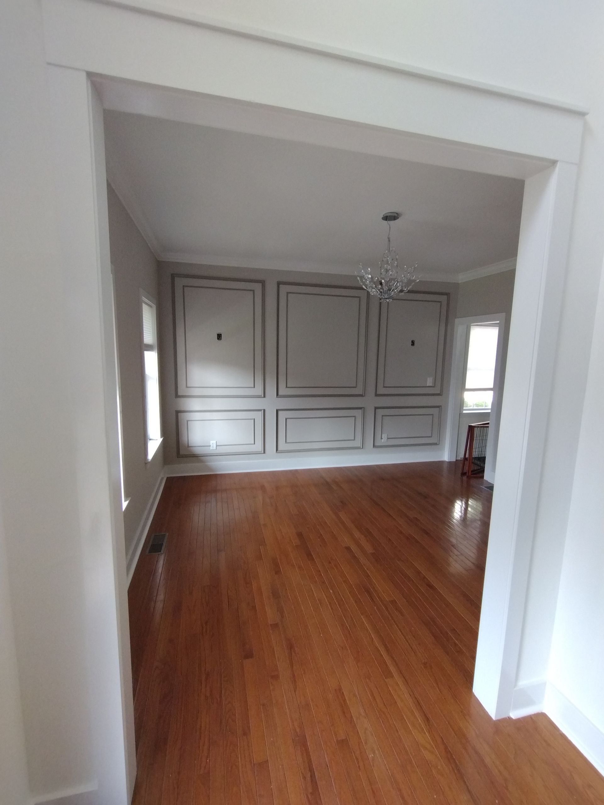 An empty room with hardwood floors and white walls.