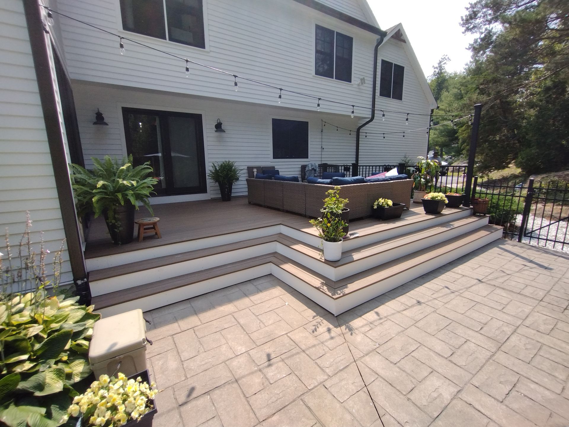 A large white house with a patio and stairs in front of it.