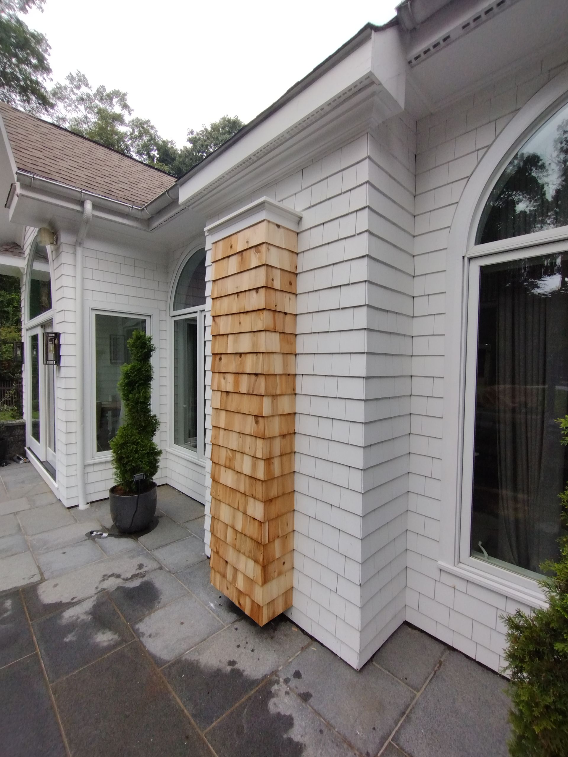 A white brick house with a wooden pillar in front of it