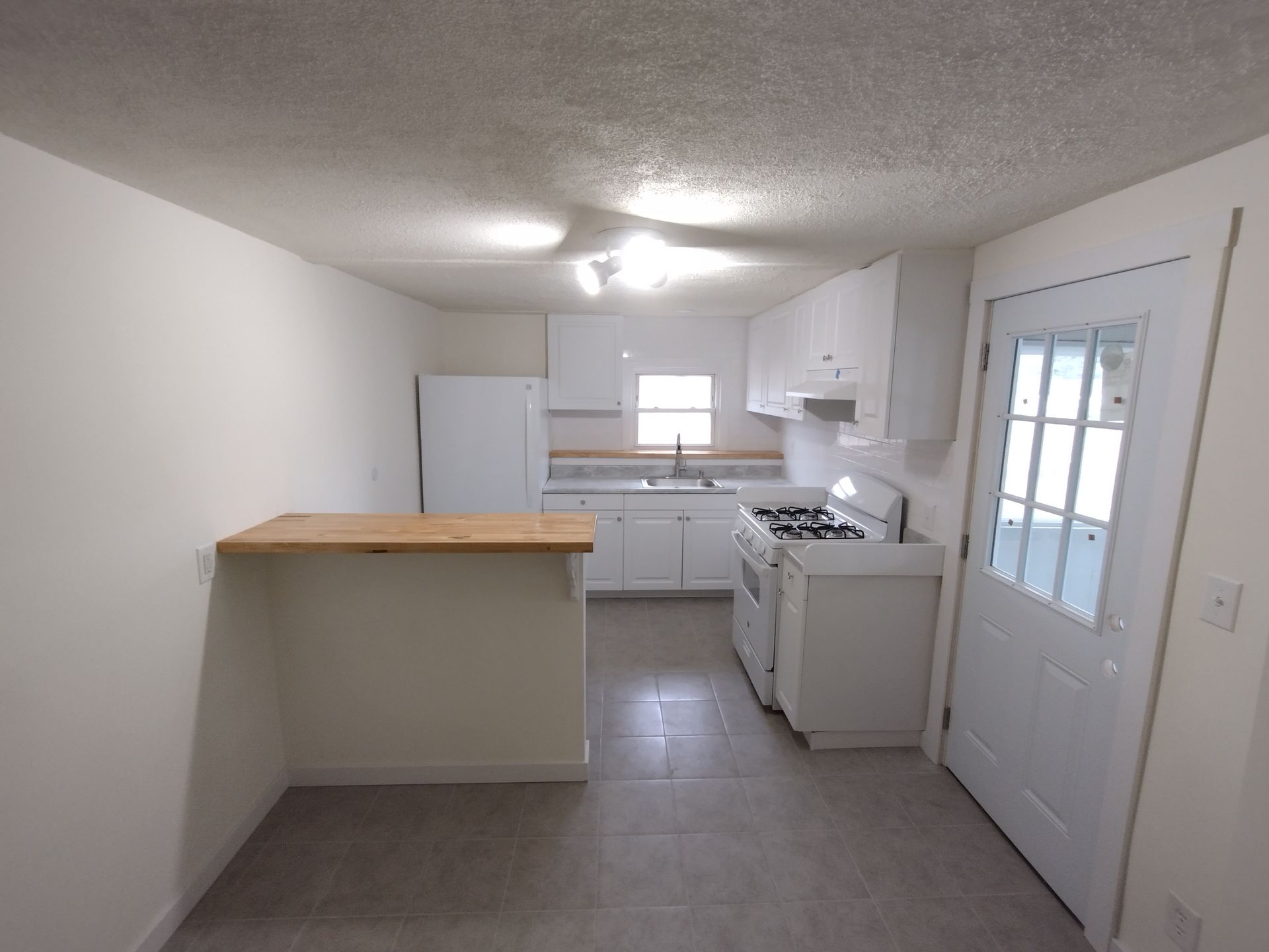 An empty kitchen with white cabinets and a stove
