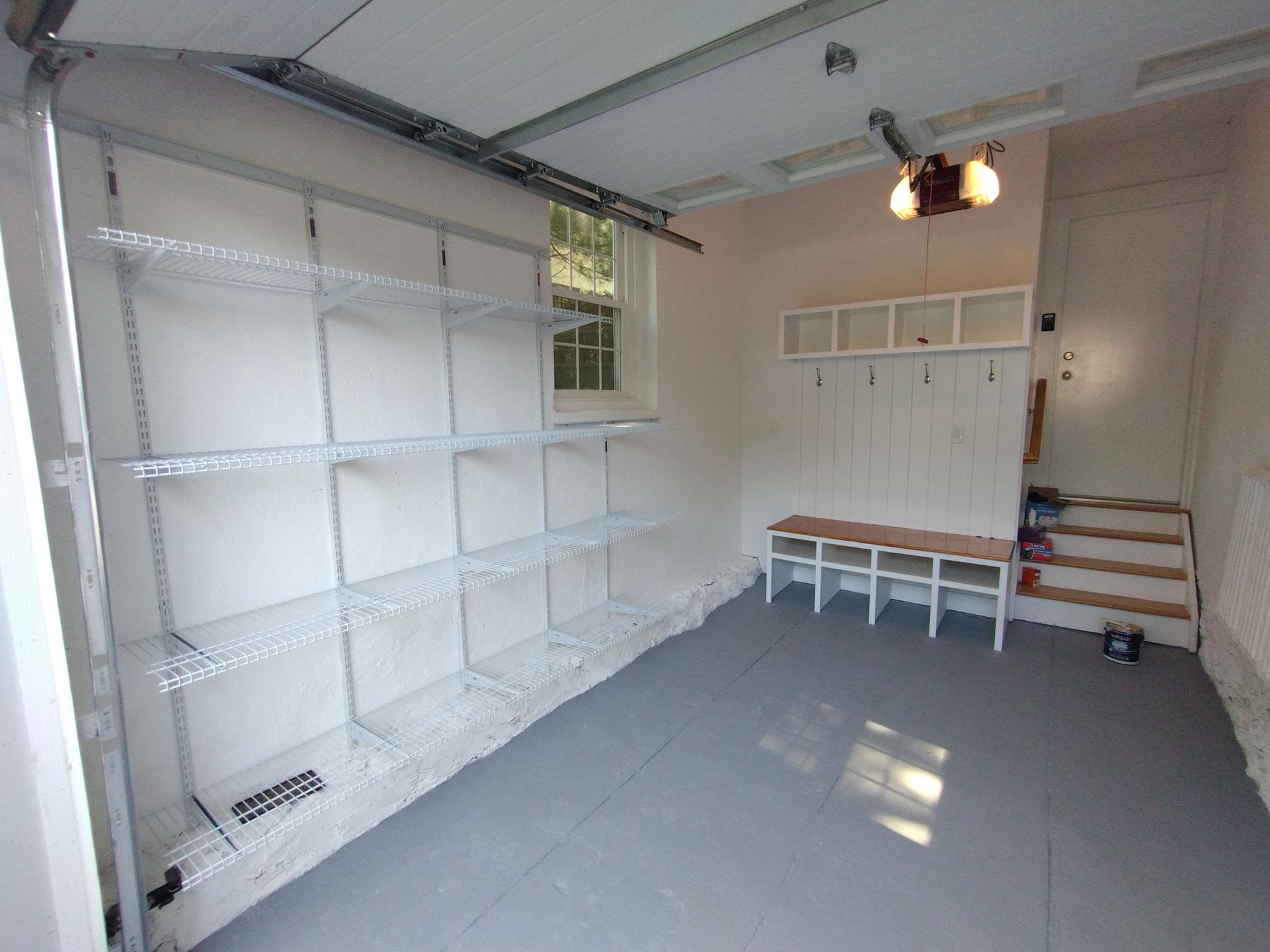 An empty garage with shelves , a bench , and stairs.