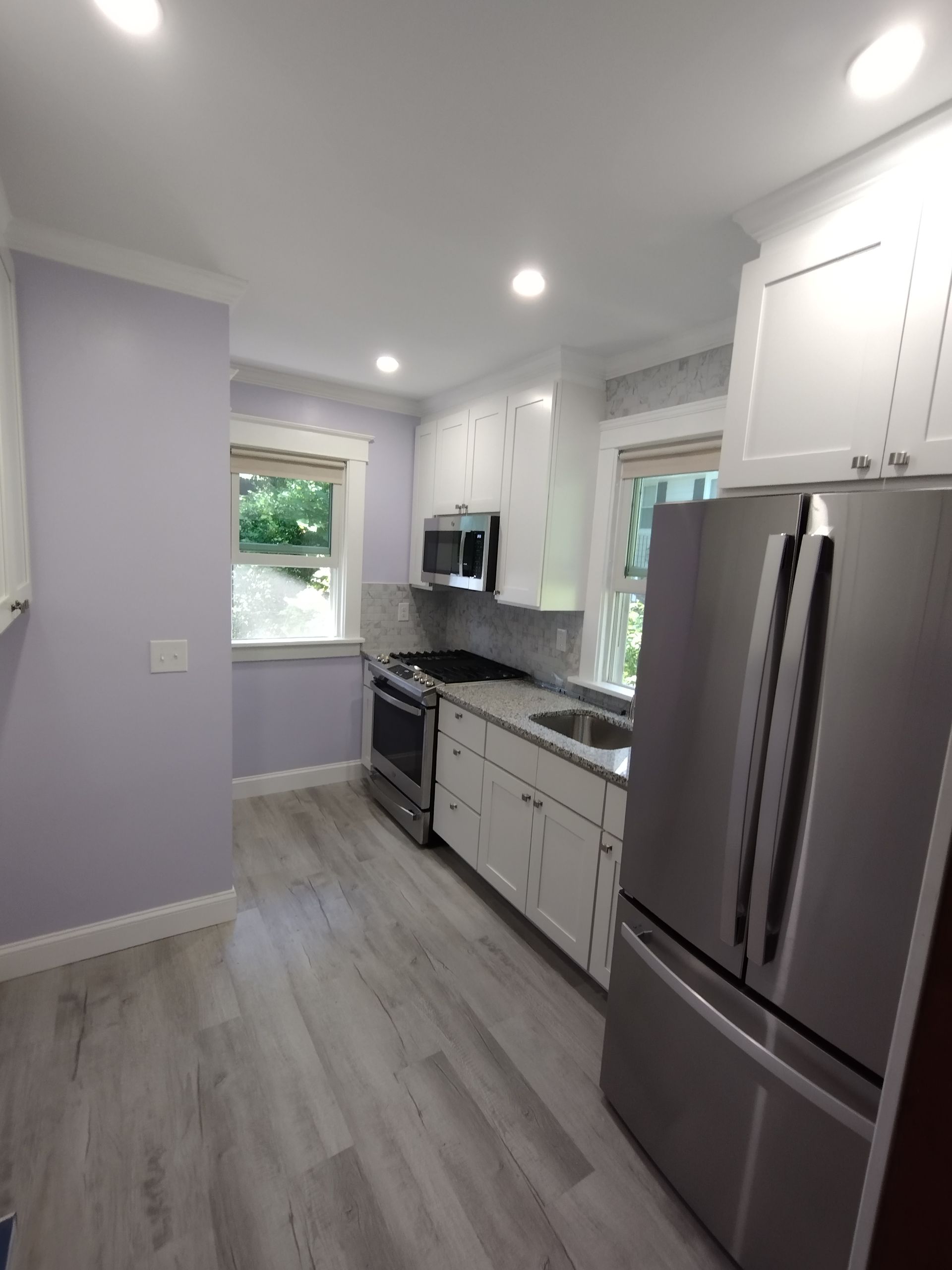 A kitchen with stainless steel appliances and purple walls