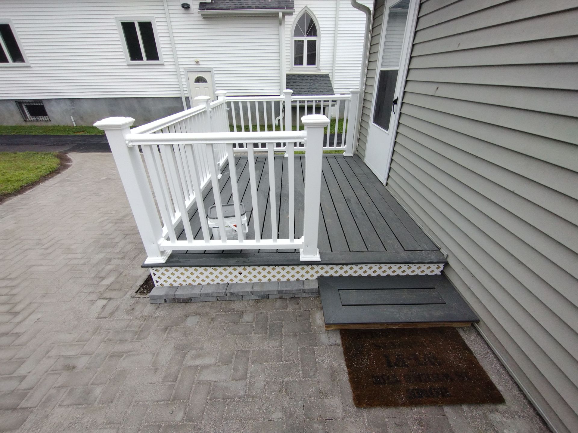 A white house with a gray deck and stairs