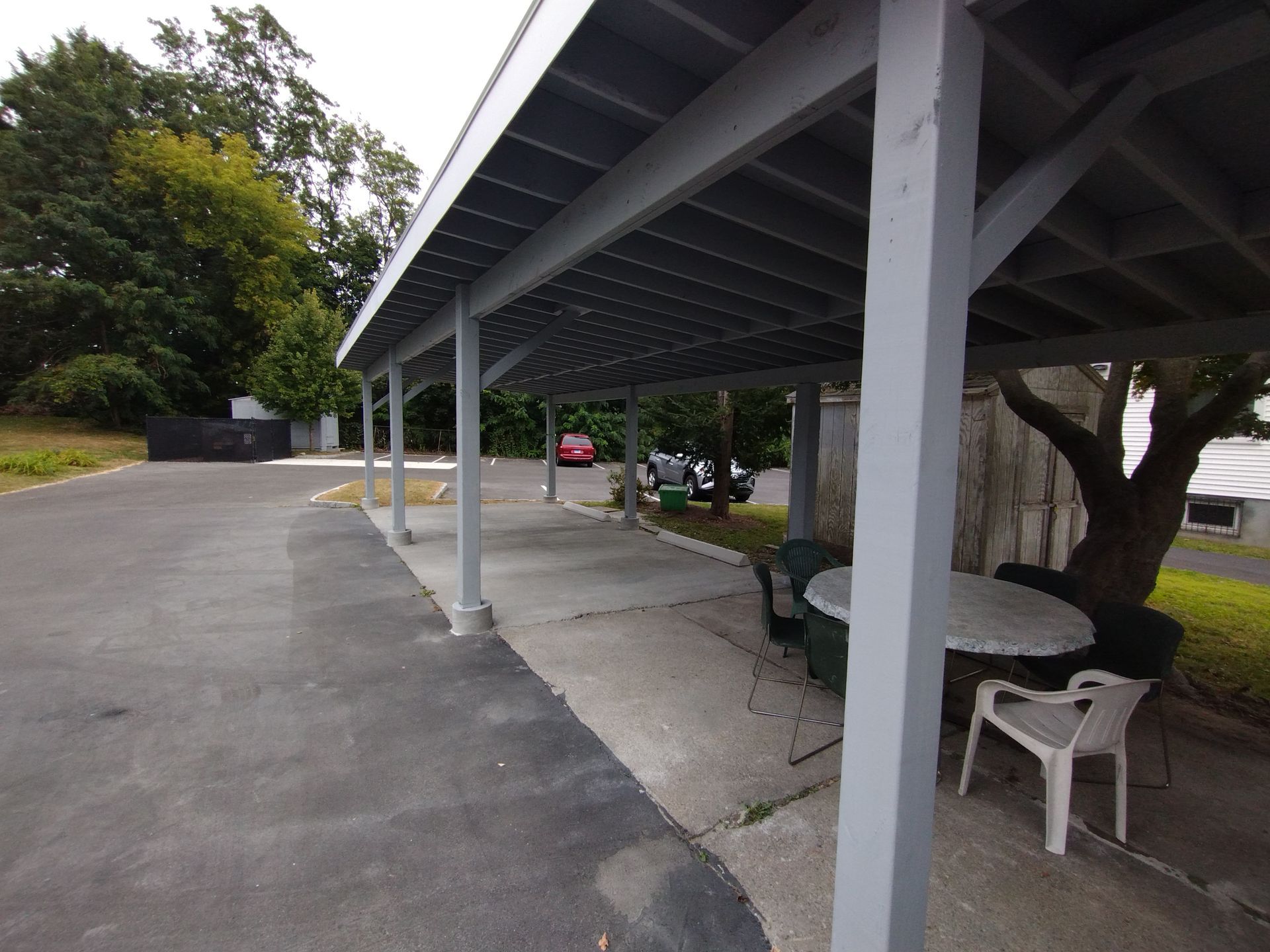 A carport with a table and chairs underneath it