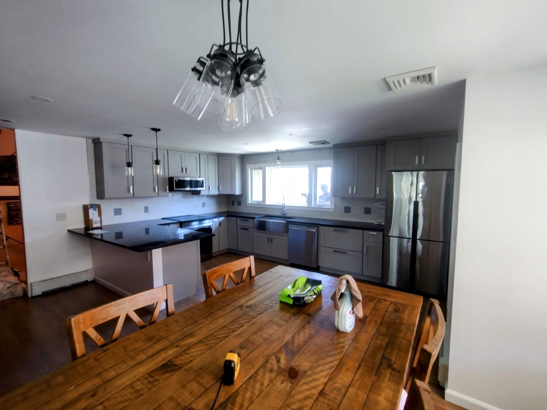 A kitchen with a wooden table and chairs and a stainless steel refrigerator.