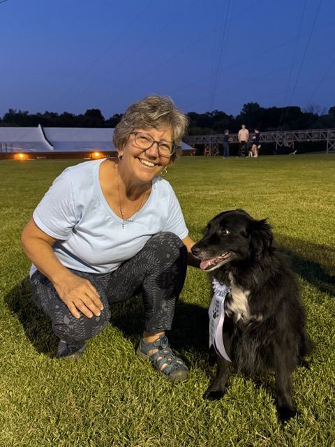A group of dogs sits in front of a display for the Milwaukee Dog Training Club.