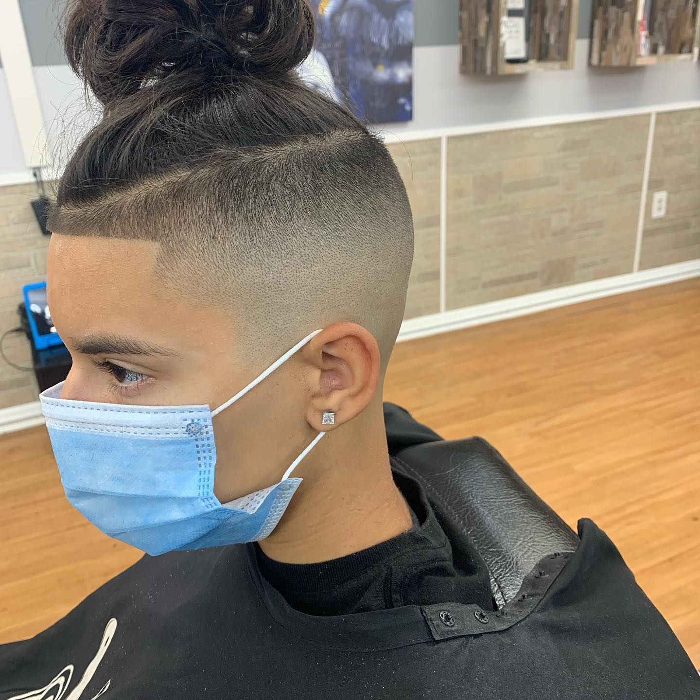 A man wearing a face mask is getting his hair cut