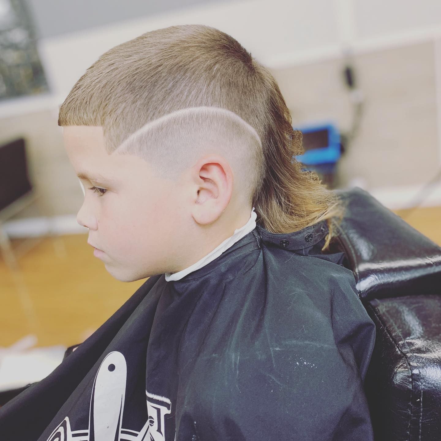 A young boy is getting his hair cut at a barber shop