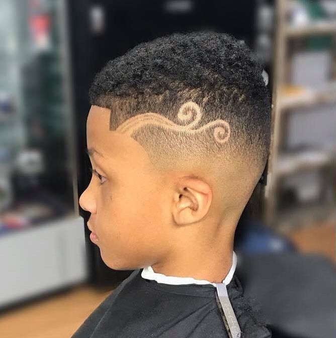 A young boy is getting his hair cut at a barber shop.