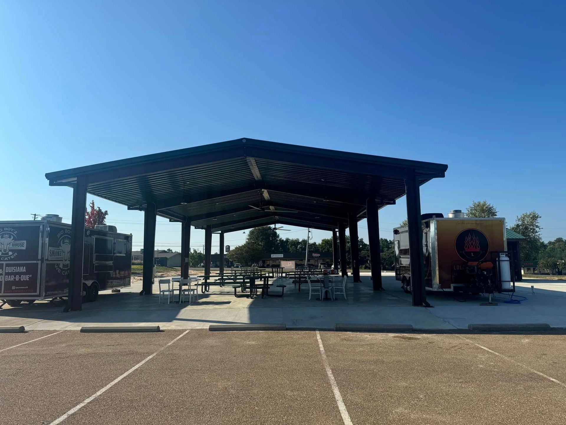 A covered area with tables and chairs in a parking lot.