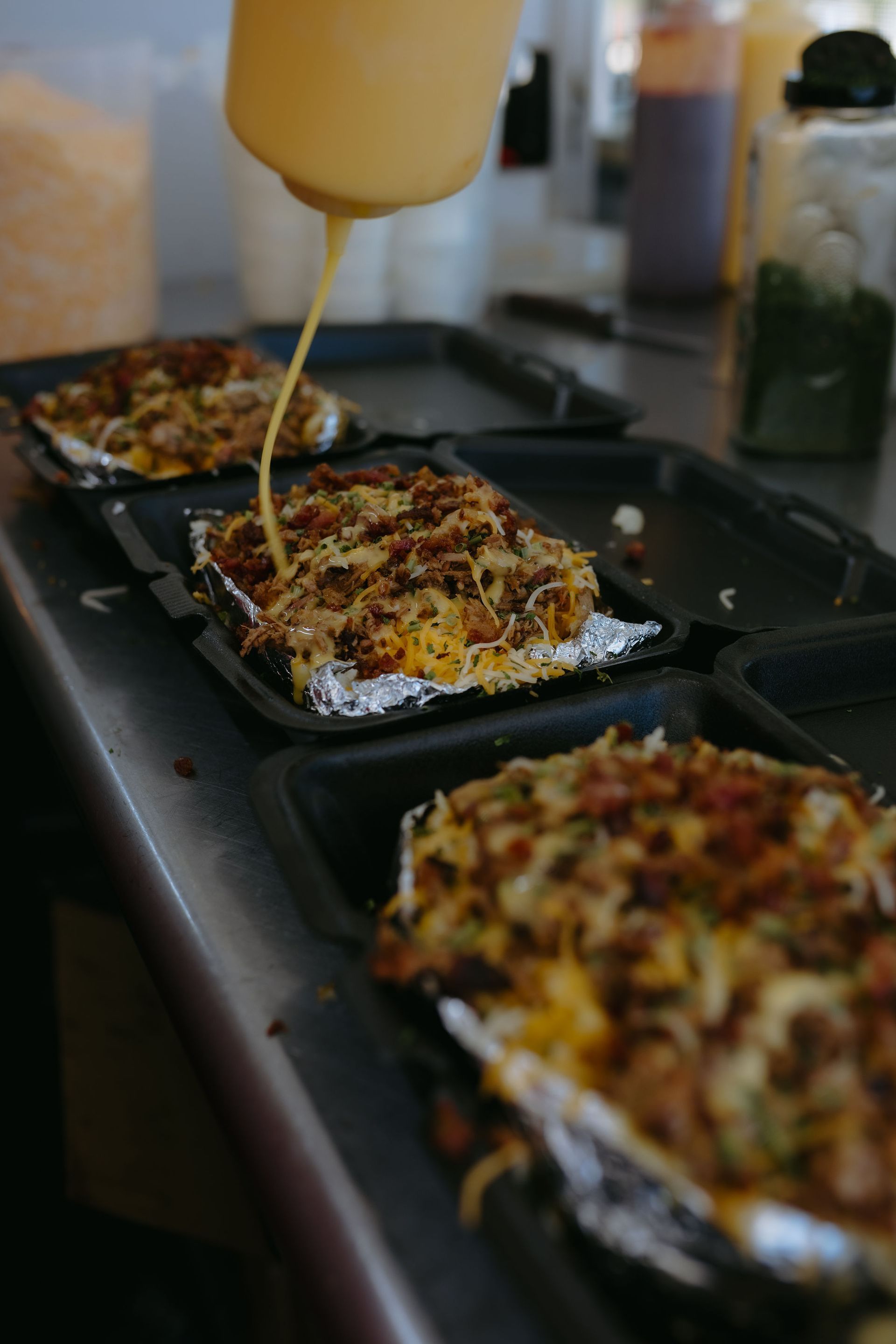Two food trucks are parked under a covered area with picnic tables.