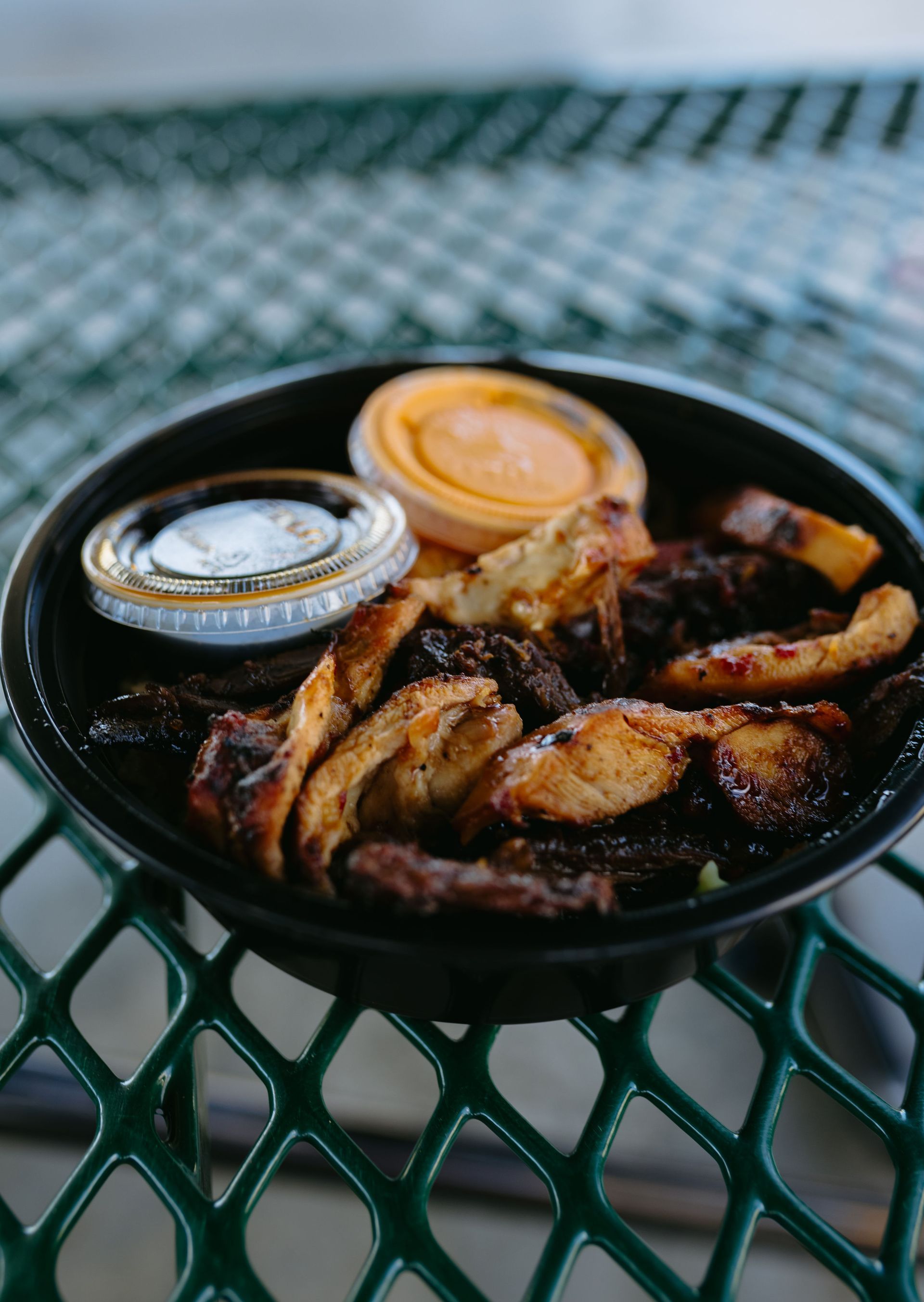 A pulled pork sandwich in a styrofoam container with onions and pickles.