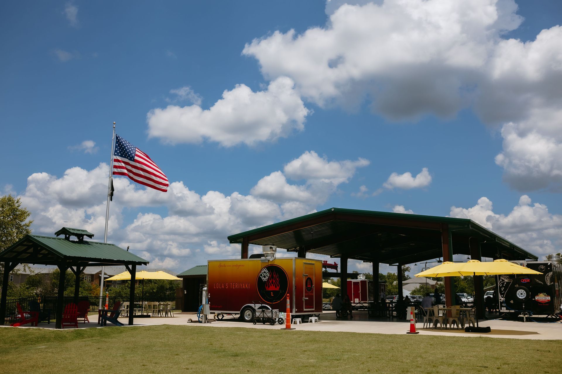 A covered area with tables and chairs in a parking lot.