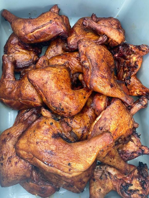 A pile of smoked chicken wings and legs in a container.