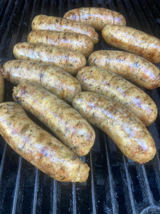 A bunch of sausages are cooking on a grill.