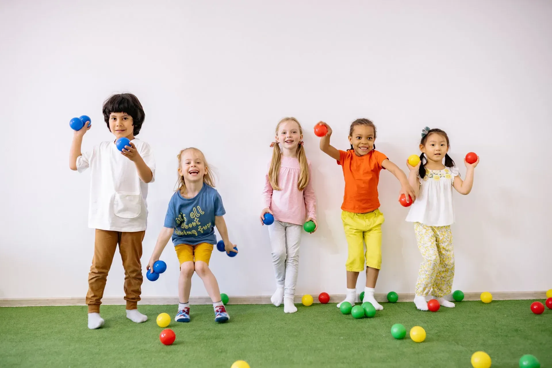 A group of children are playing with dumbbells in a gym.