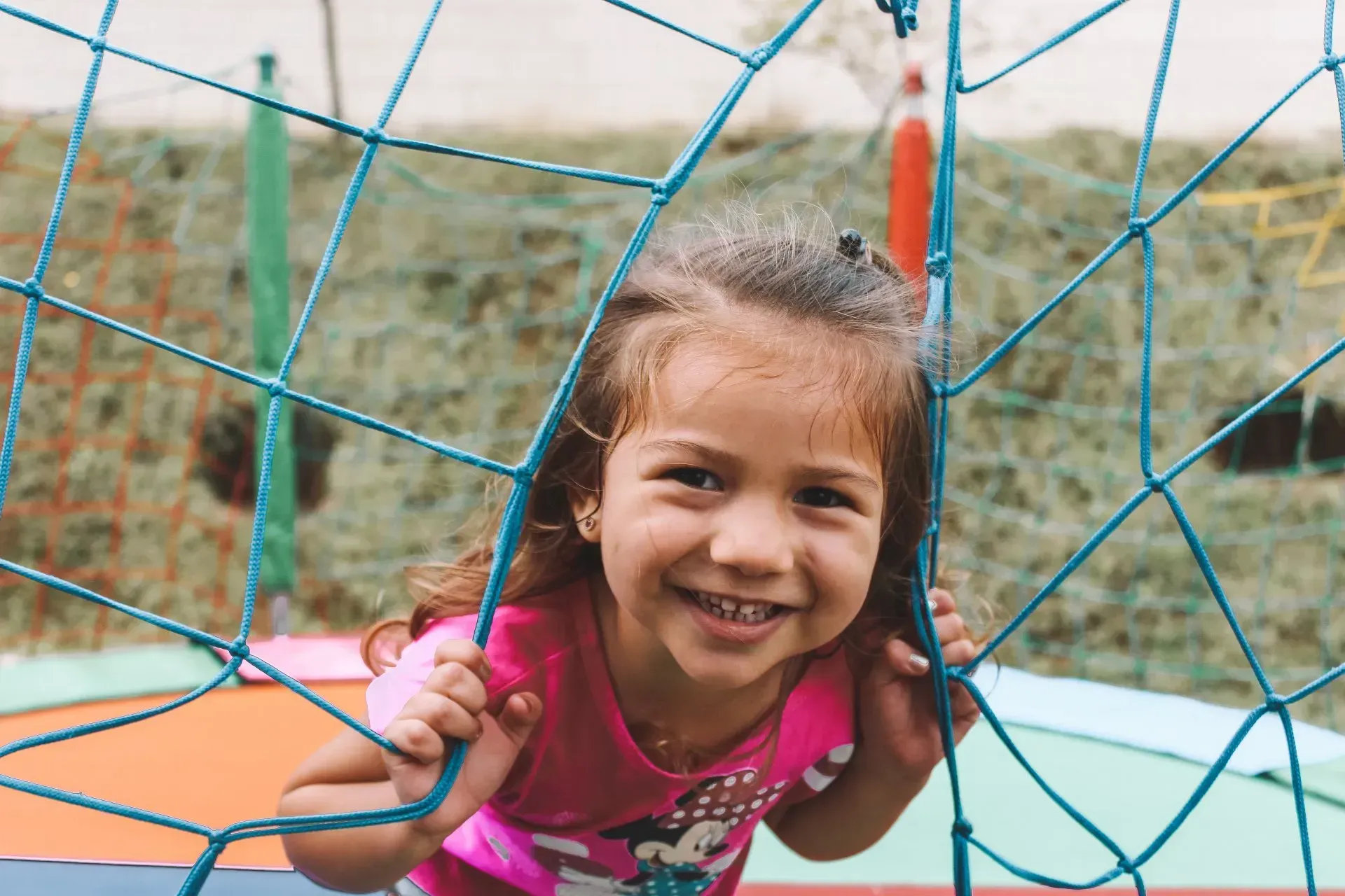 A little girl is smiling while playing on a trampoline.