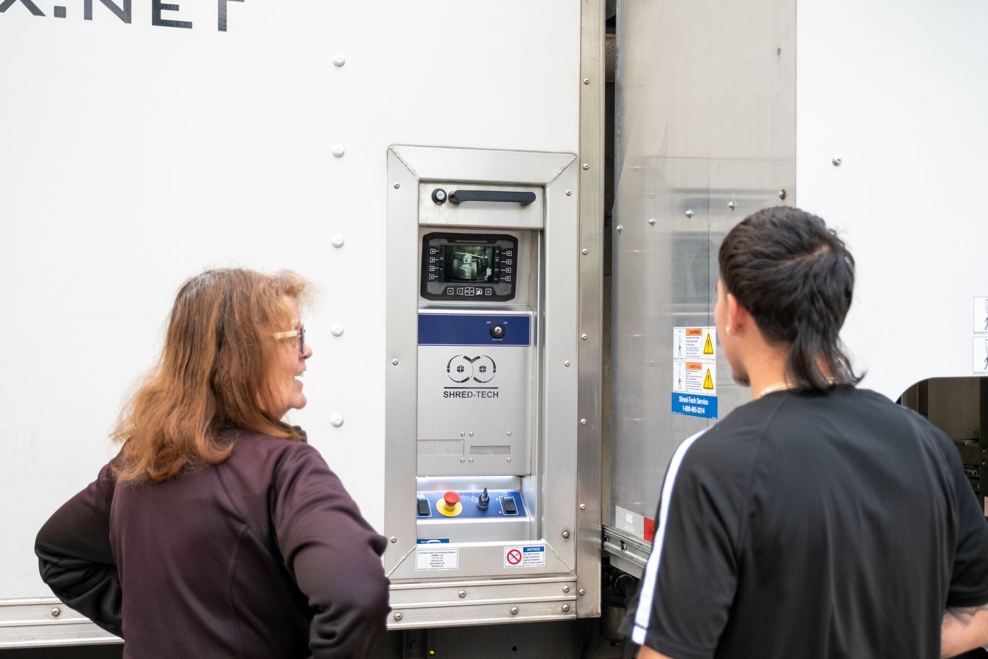 A man and a woman are standing in front of a white truck.