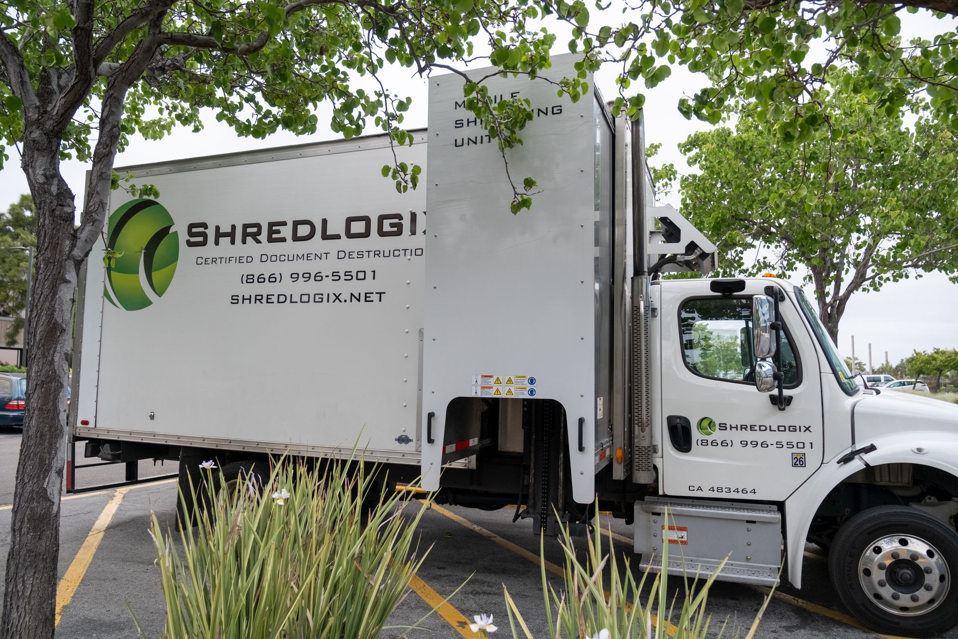 A white shredding truck is parked in a parking lot
