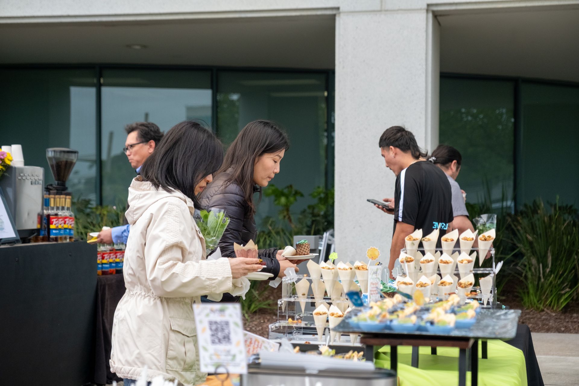 A group of people are standing around a table eating food.