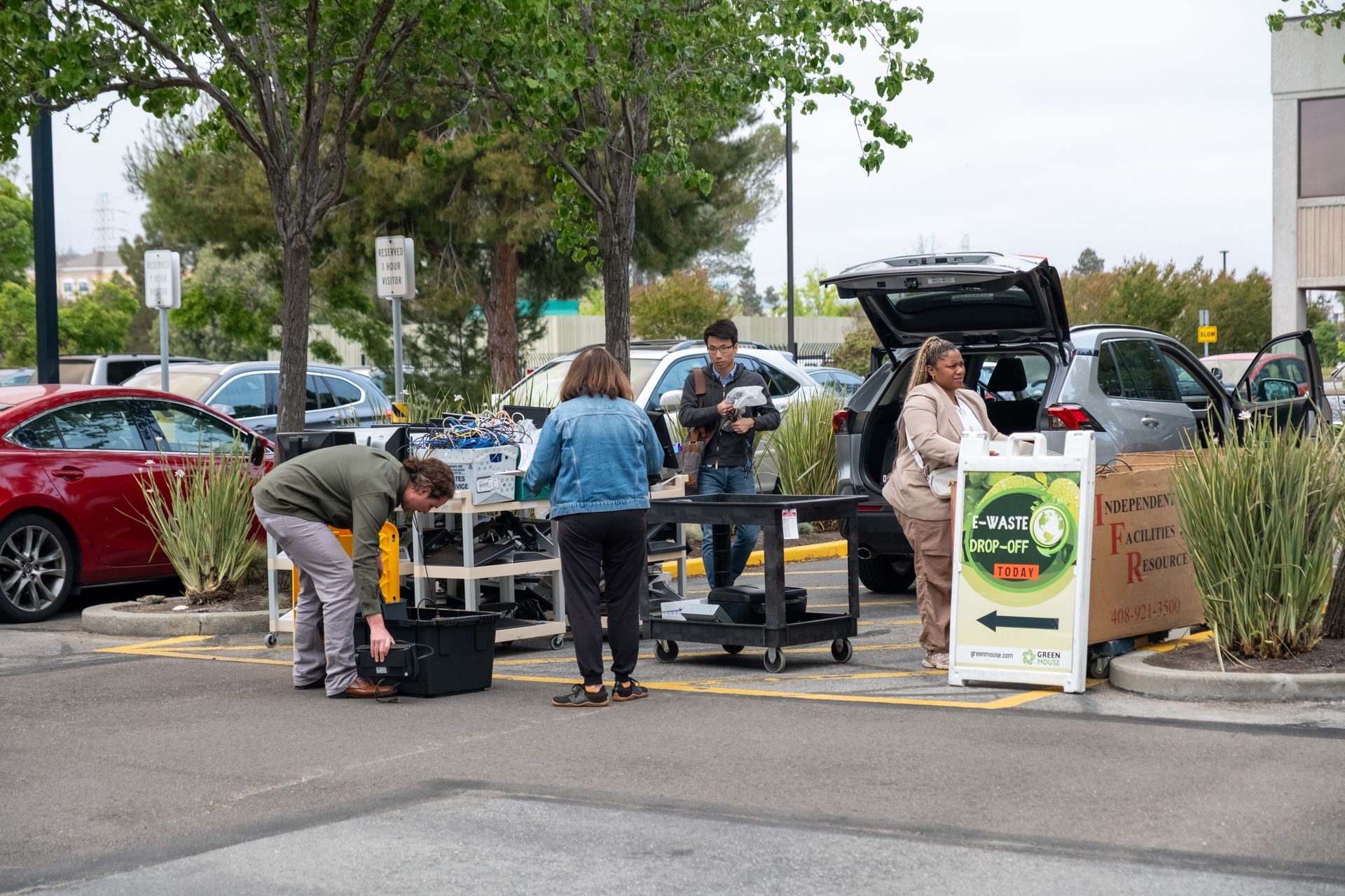 A group of people are standing around a table in a parking lot.