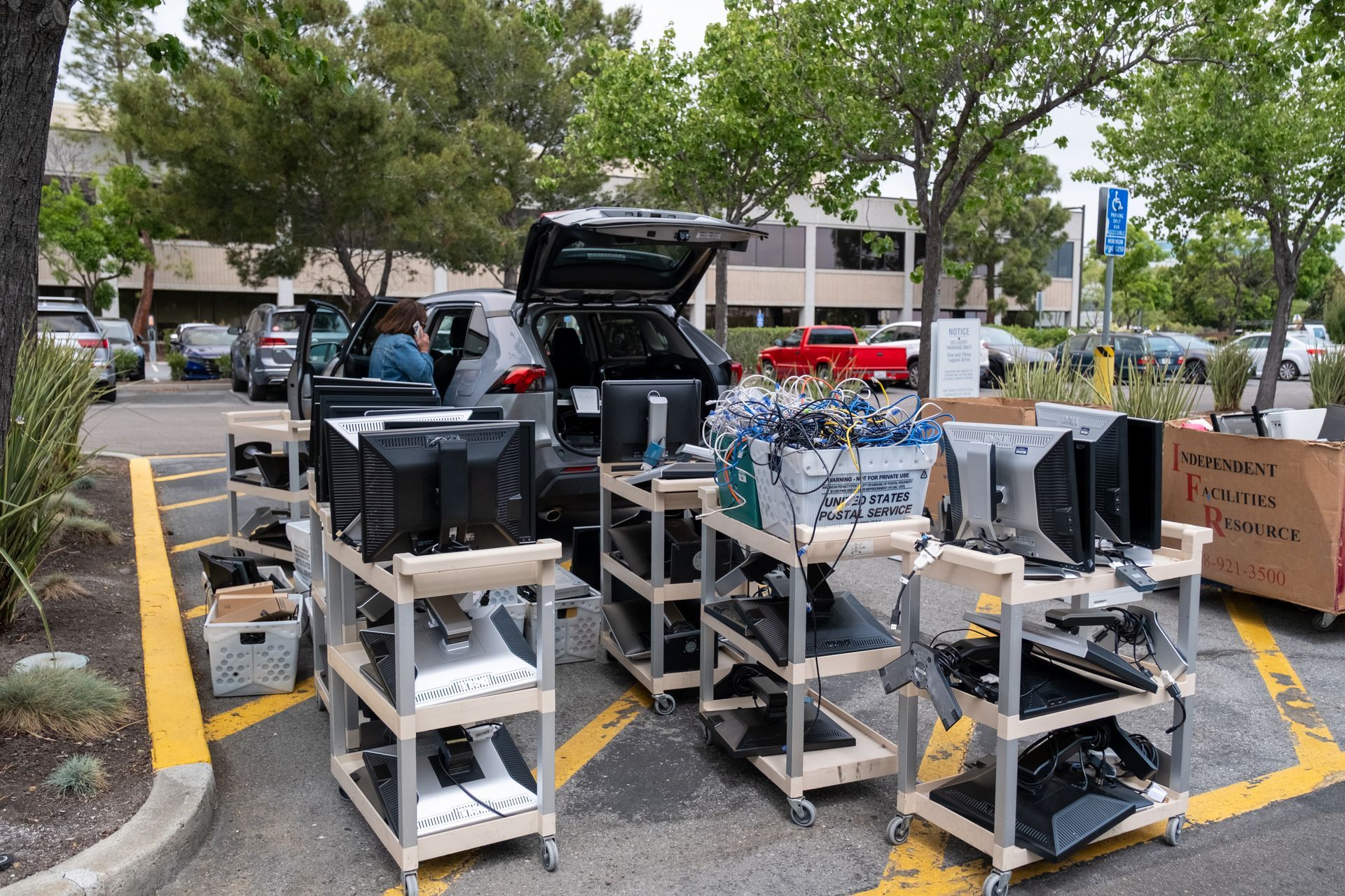 A bunch of computers are on carts in a parking lot