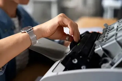 Person feeding documents into a shredder, illustrating the convenience of a mobile shredding service.
